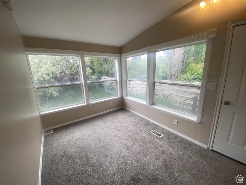 Unfurnished sunroom with vaulted ceiling, carpet floors, and baseboards