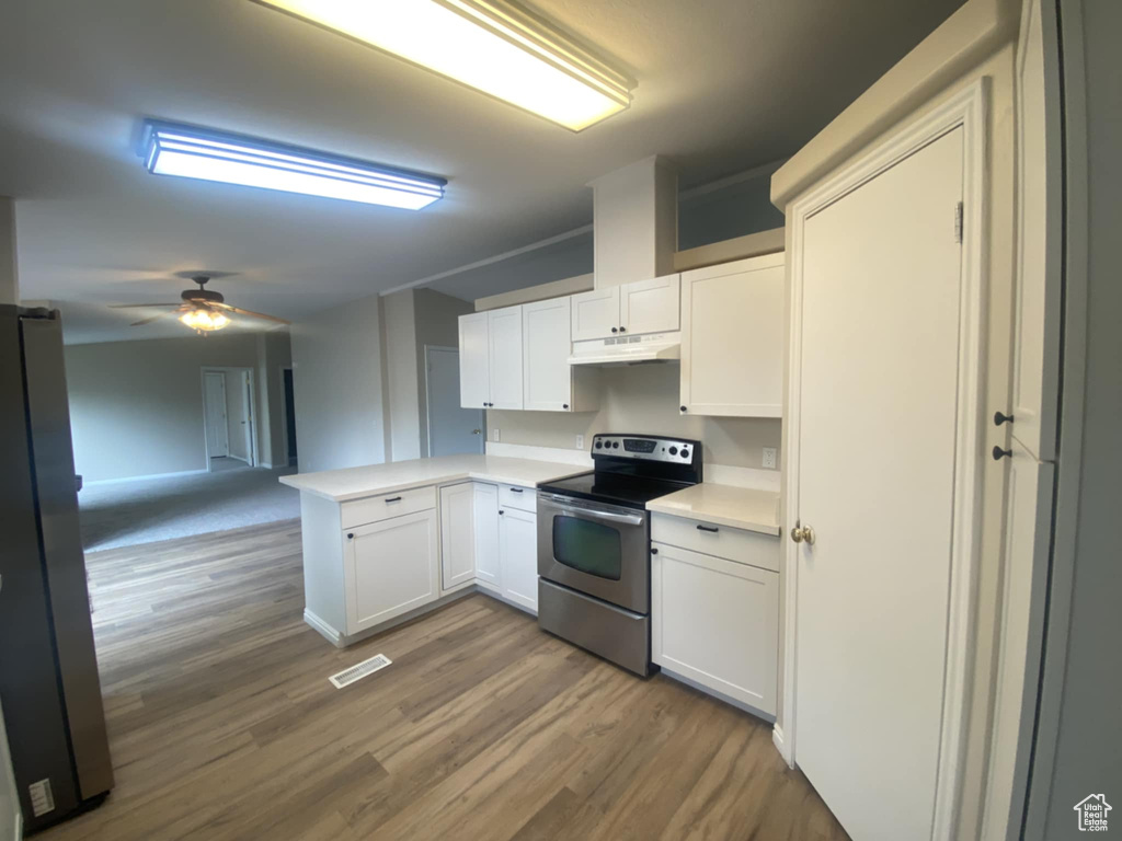 Kitchen with stainless steel appliances, under cabinet range hood, a peninsula, and wood finished floors