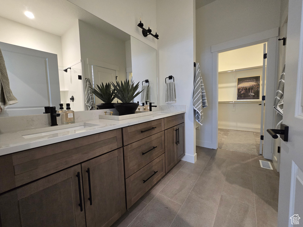 Bathroom featuring double vanity, a spacious closet, baseboards, and tile patterned flooring