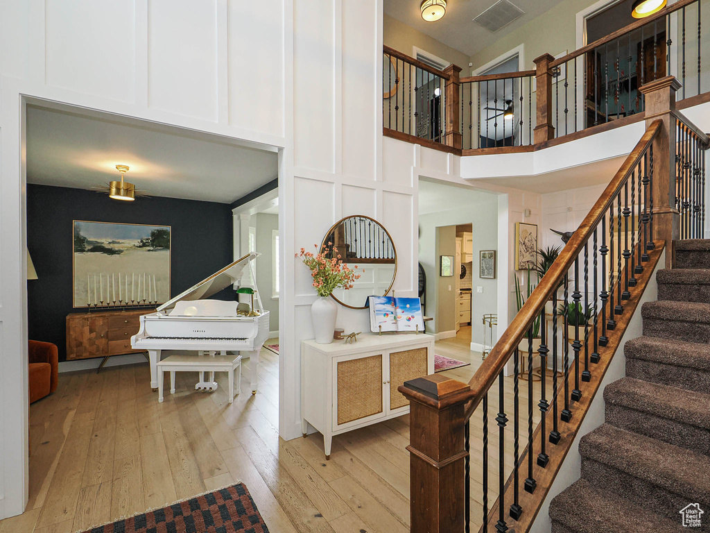 Stairway with a towering ceiling and wood-type flooring