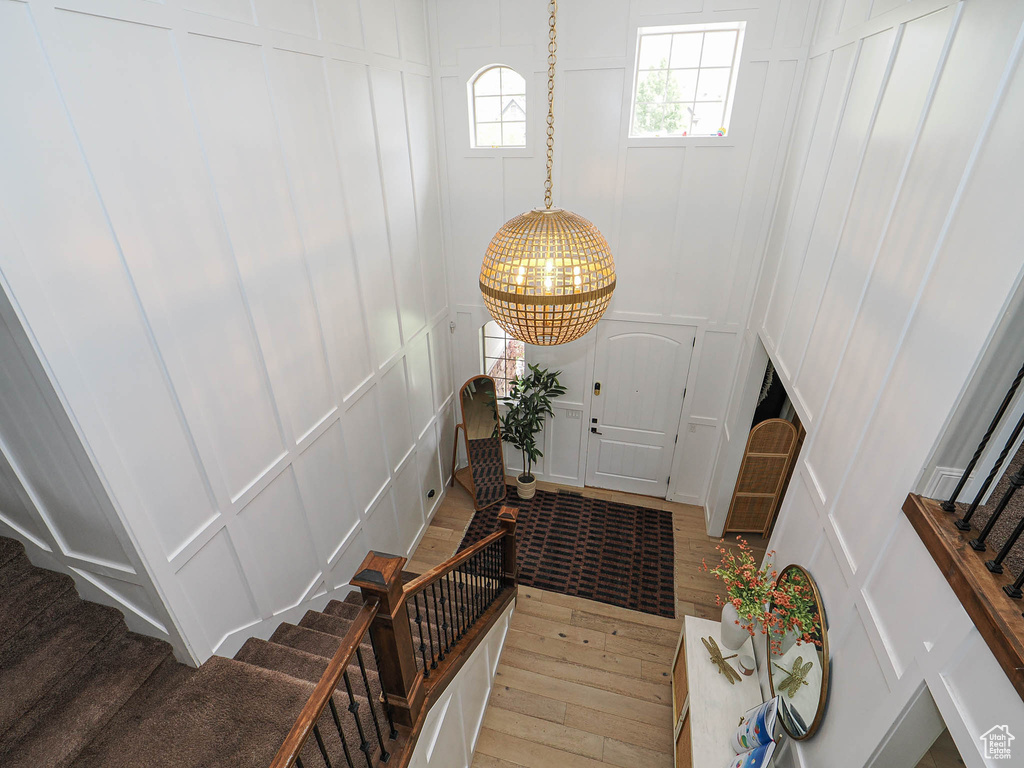 Foyer entrance with a decorative wall, light wood-style flooring, stairs, and a chandelier