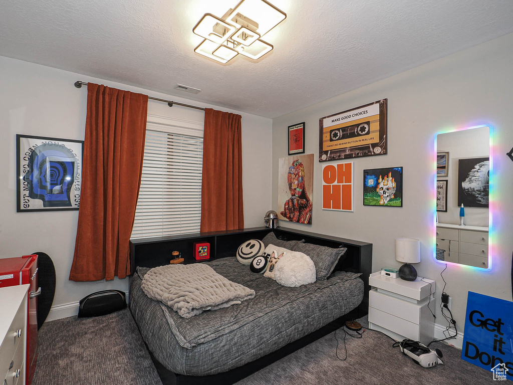 Carpeted bedroom featuring baseboards and a textured ceiling