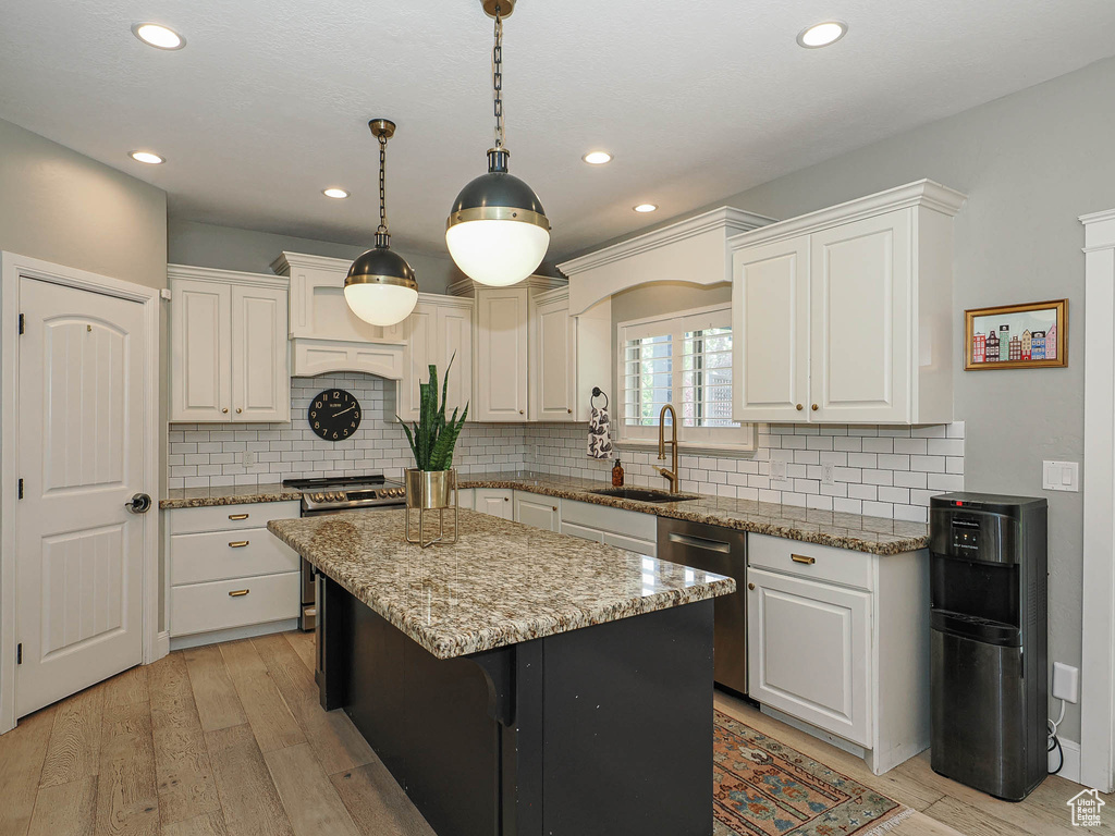 Kitchen with a sink, stainless steel appliances, white cabinets, a kitchen island, and recessed lighting