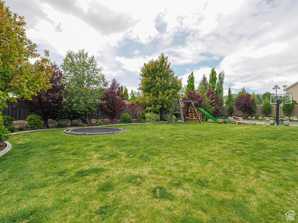 View of yard featuring a playground and a trampoline