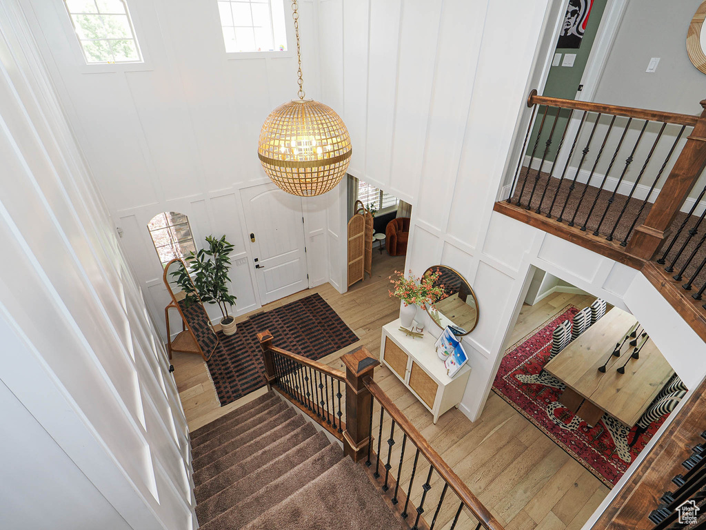 Stairs featuring a decorative wall, a chandelier, and wood finished floors