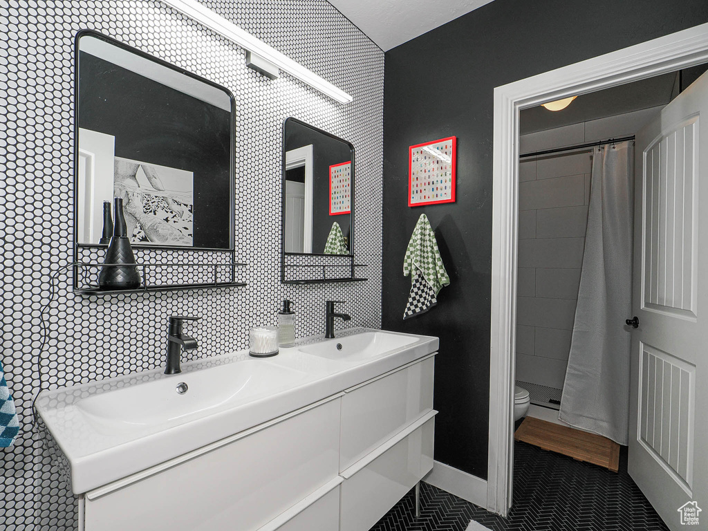 Bathroom with toilet, double vanity, curtained shower, and tile patterned flooring