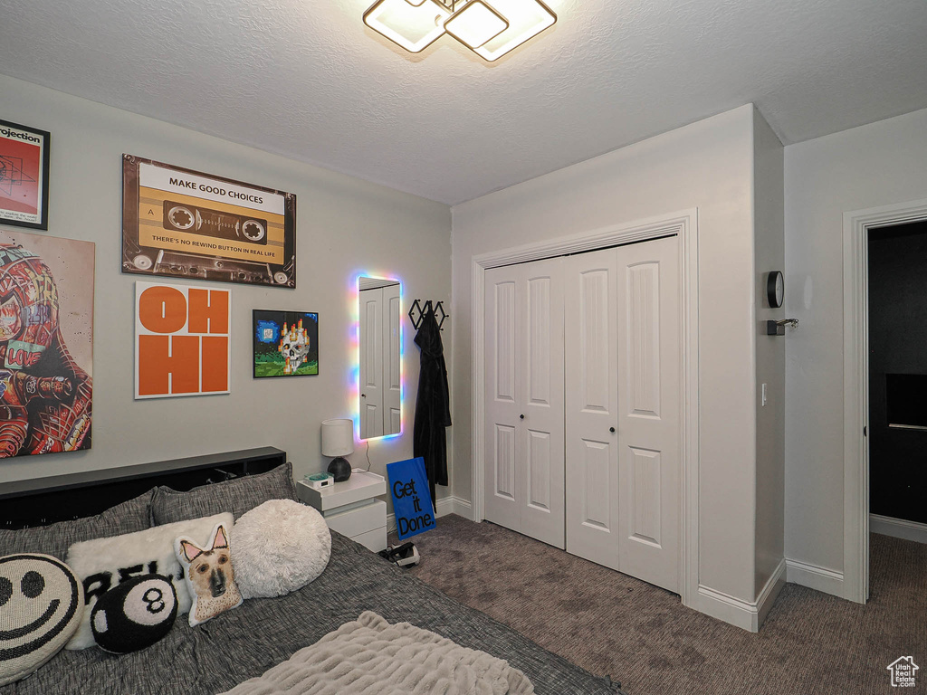 Bedroom with carpet, a closet, baseboards, and a textured ceiling
