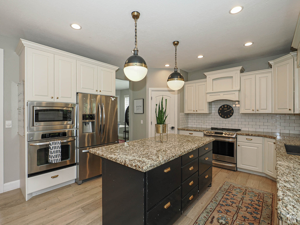 Kitchen with stainless steel appliances, dark cabinetry, white cabinetry, light wood-type flooring, and recessed lighting