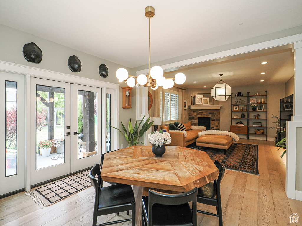 Dining area with french doors, light wood-style flooring, a fireplace, and recessed lighting