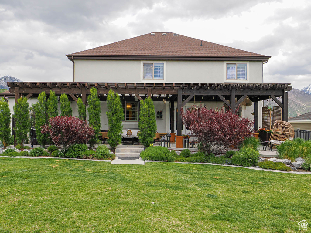 Back of property with a pergola, stucco siding, a lawn, and a patio area