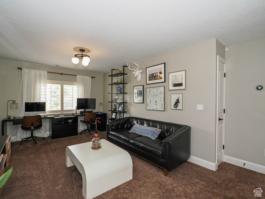 Carpeted living area featuring a desk and baseboards
