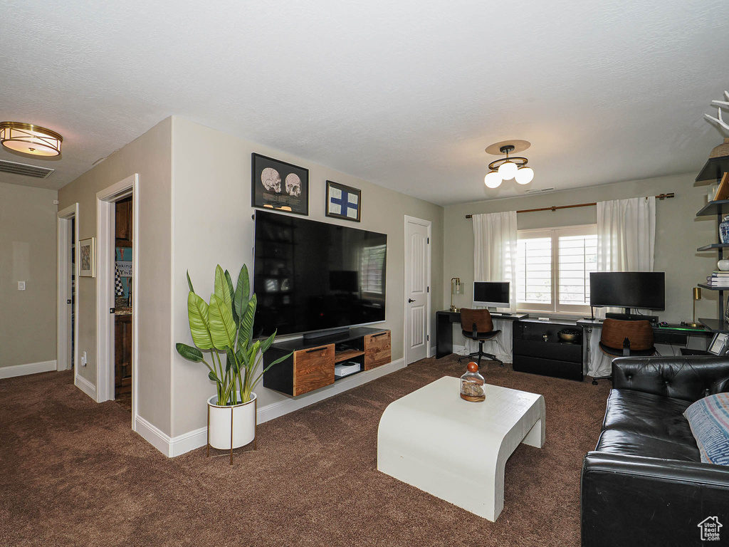 Carpeted living area with a desk and baseboards