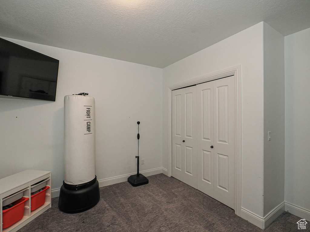 Miscellaneous room with dark colored carpet and baseboards