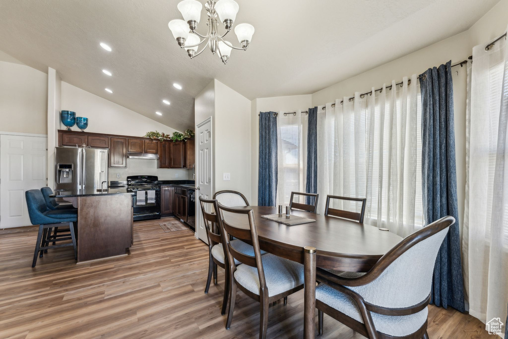 Dining space featuring a chandelier, plenty of natural light, vaulted ceiling, light wood-style flooring, and recessed lighting