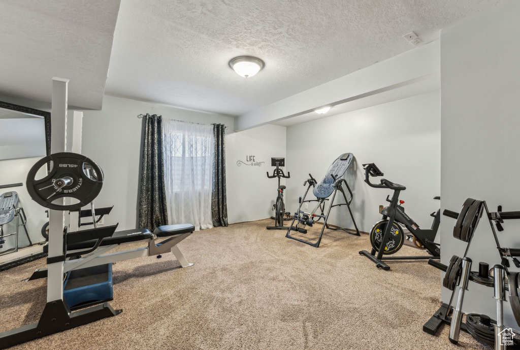 Exercise room with carpet flooring and a textured ceiling