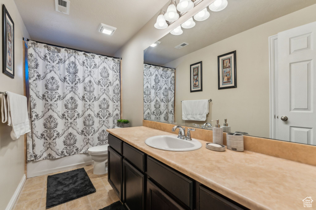 Bathroom featuring vanity, toilet, tile patterned flooring, and baseboards