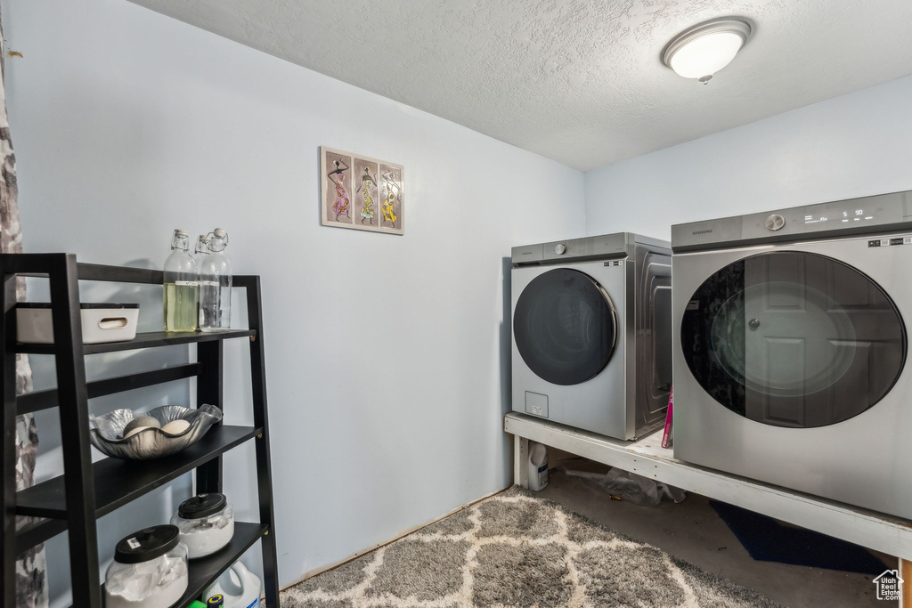 Laundry area with independent washer and dryer and a textured ceiling