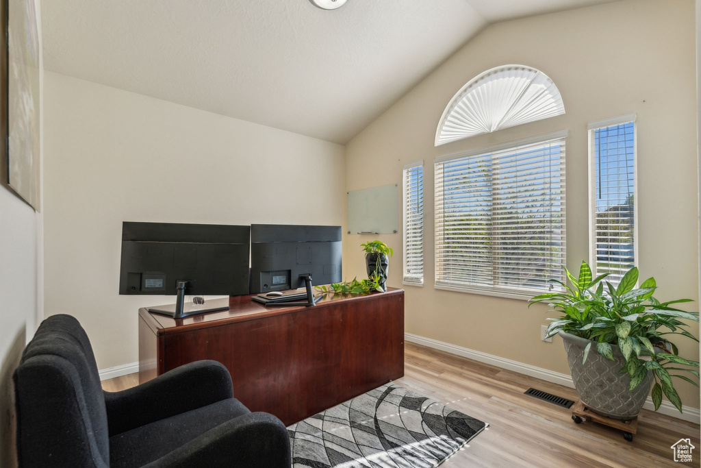 Home office featuring light wood-type flooring, baseboards, and high vaulted ceiling