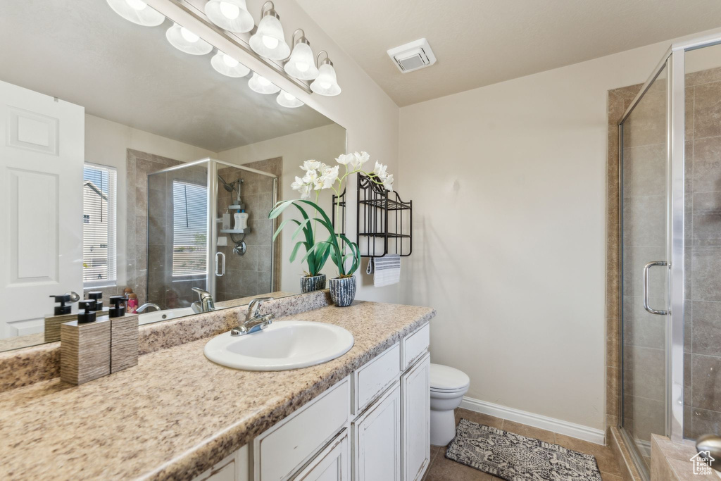 Bathroom with a shower stall, toilet, vanity, and tile patterned floors