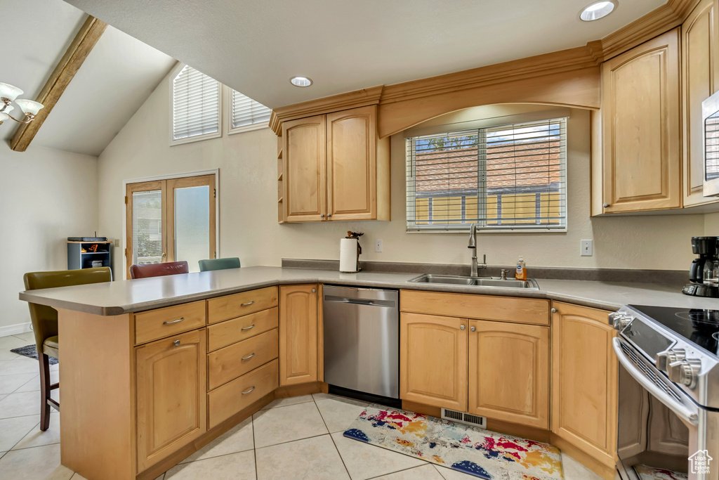Kitchen with appliances with stainless steel finishes, a sink, a peninsula, light tile patterned floors, and lofted ceiling