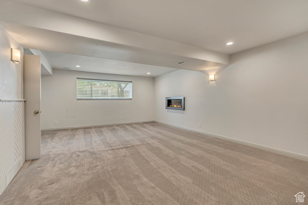 Basement featuring light carpet, a glass covered fireplace, recessed lighting, and baseboards