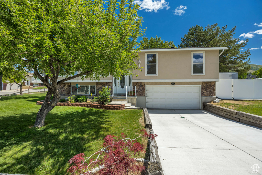View of front of home featuring an attached garage, stucco siding, concrete driveway, and stone siding