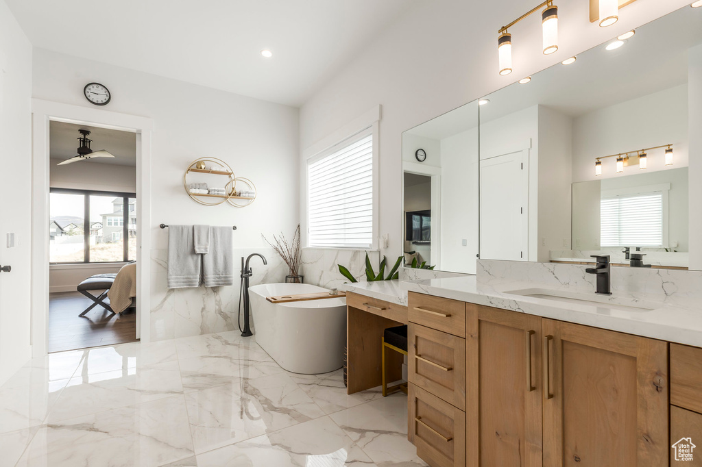 Full bathroom with ensuite bathroom, a freestanding bath, ceiling fan, marble tiled floors, and vanity