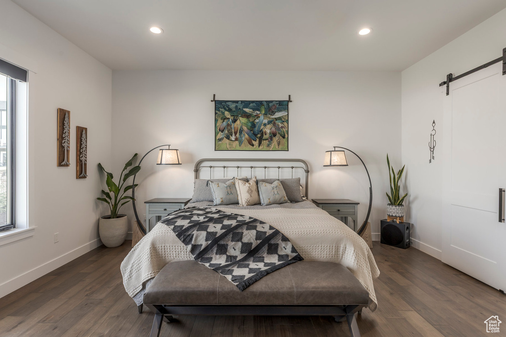 Bedroom featuring a barn door, wood finished floors, recessed lighting, and baseboards