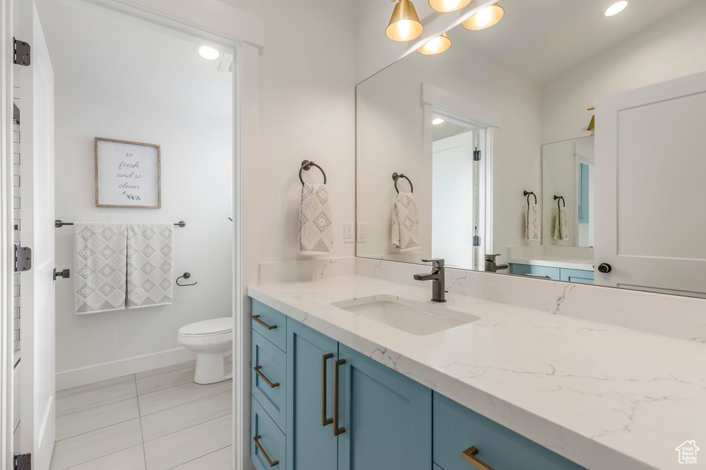Bathroom featuring toilet, vanity, tile patterned flooring, baseboards, and recessed lighting