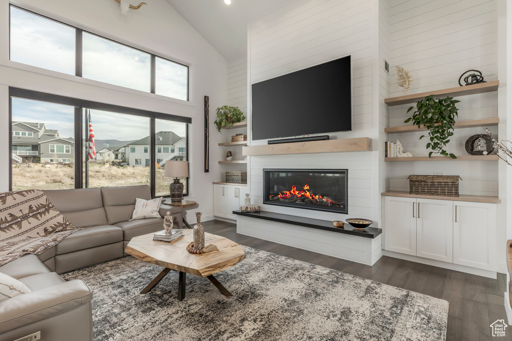Living area with a large fireplace, dark wood finished floors, high vaulted ceiling, and recessed lighting