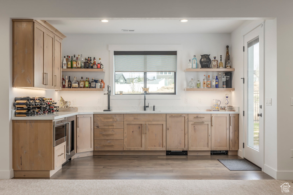 Indoor wet bar with plenty of natural light, recessed lighting, and wood finished floors