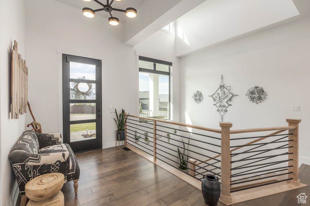 Living area with an upstairs landing, wood finished floors, a chandelier, and baseboards