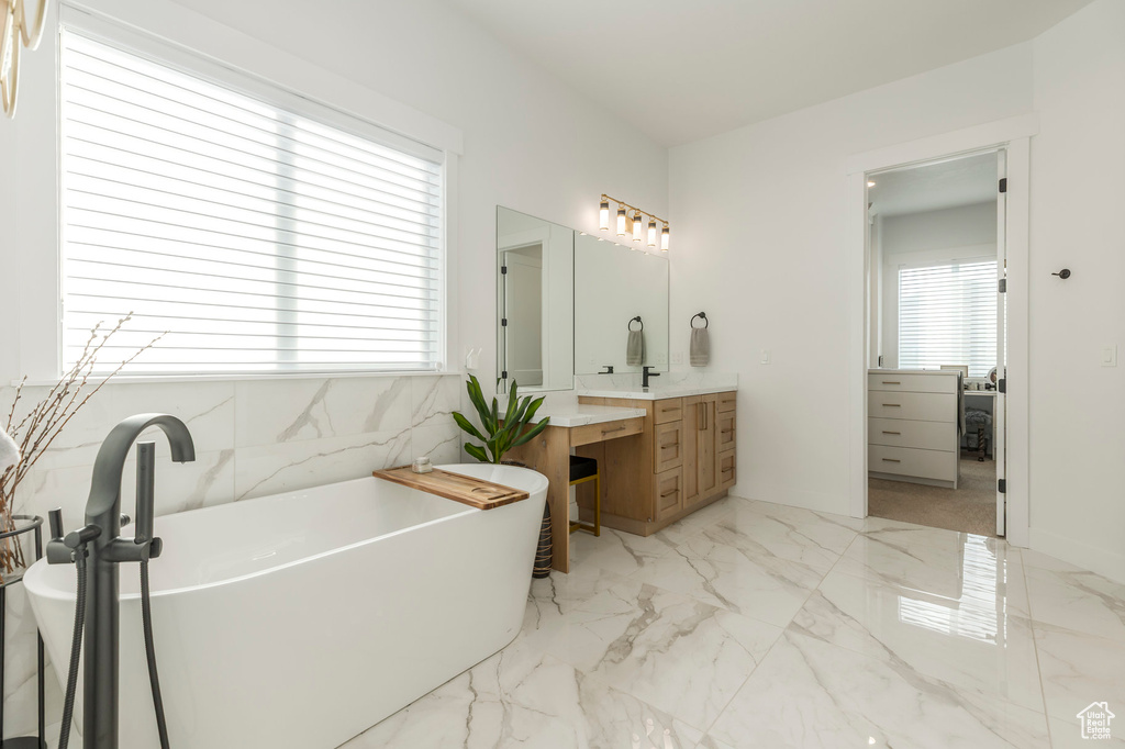 Full bathroom with vanity, a freestanding bath, and marble finish floors