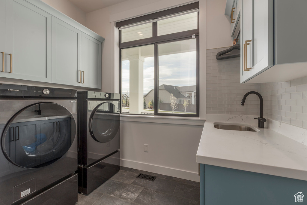 Laundry area with cabinet space, washing machine and clothes dryer, baseboards, and dark stone finish flooring