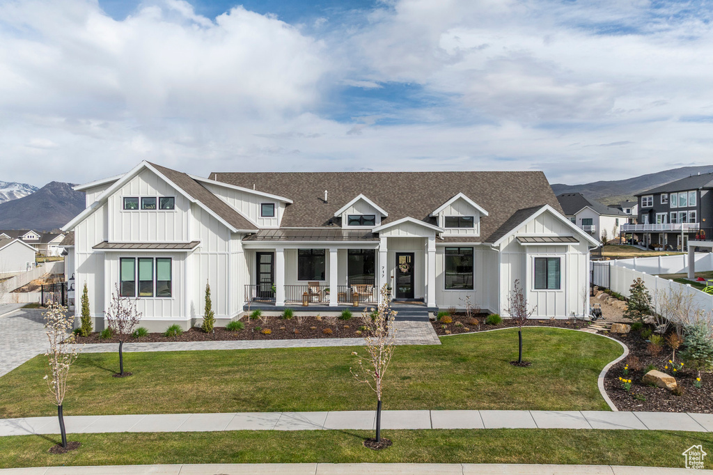 Modern inspired farmhouse featuring board and batten siding, a porch, a standing seam roof, metal roof, and a mountain view