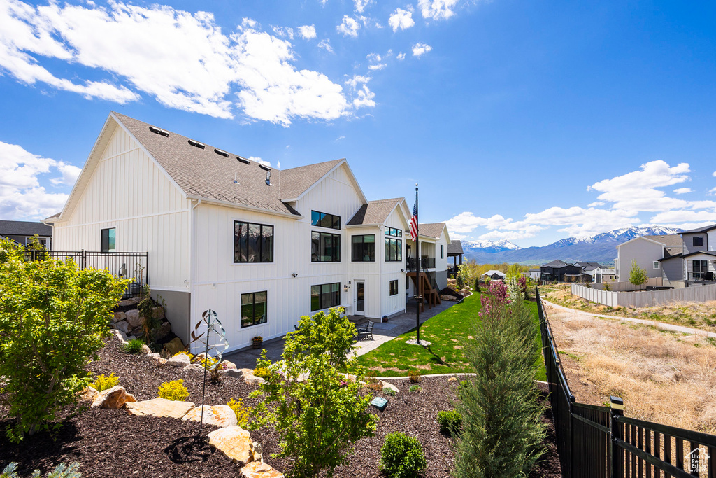 Back of house featuring a shingled roof, a mountain view, a patio, and a fenced backyard