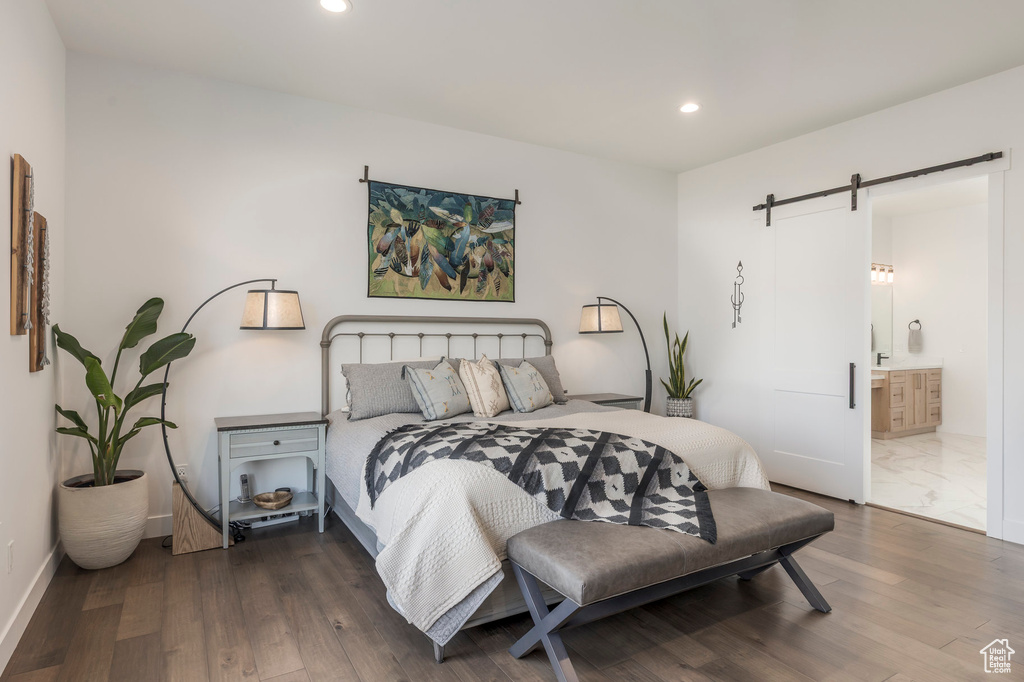 Bedroom featuring a barn door, recessed lighting, wood finished floors, ensuite bath, and baseboards