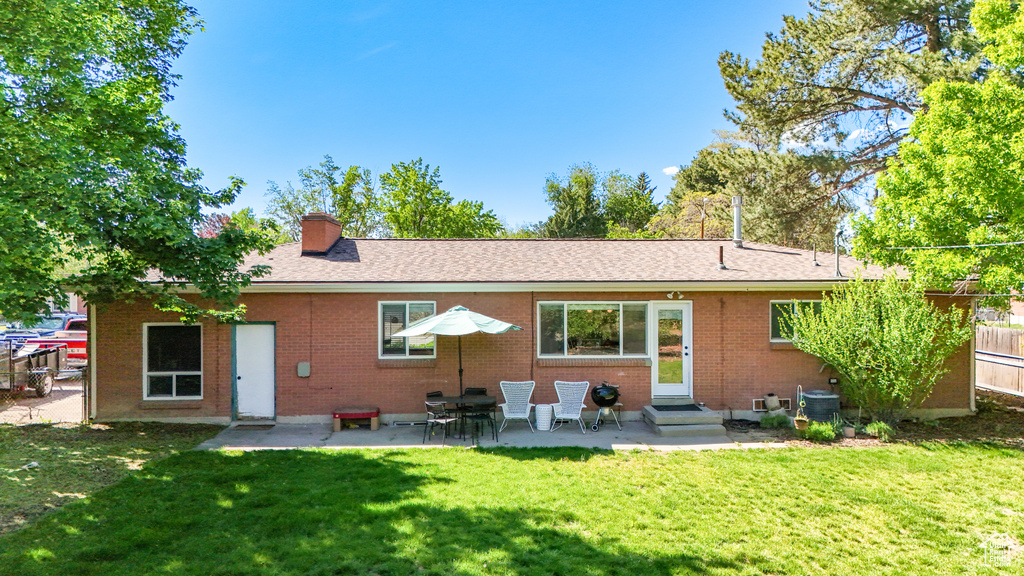 Back of property featuring brick siding, entry steps, a chimney, a patio area, and a shingled roof