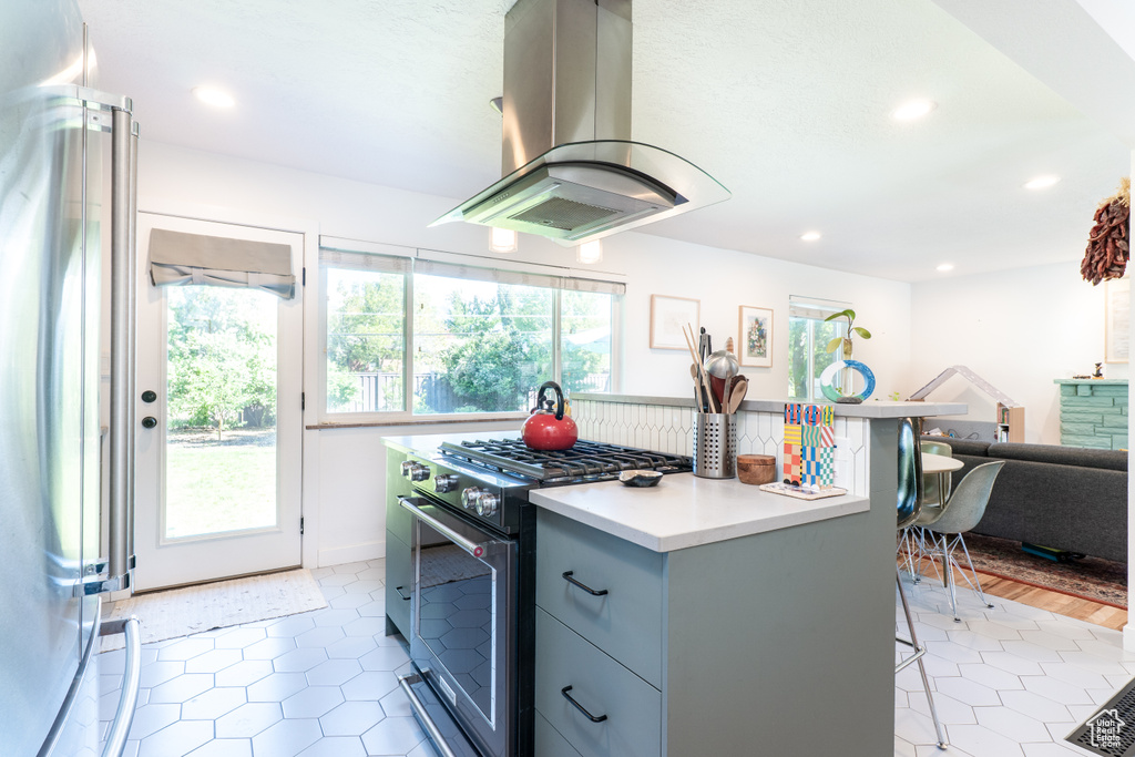 Kitchen featuring appliances with stainless steel finishes, island exhaust hood, light countertops, recessed lighting, and light tile patterned floors
