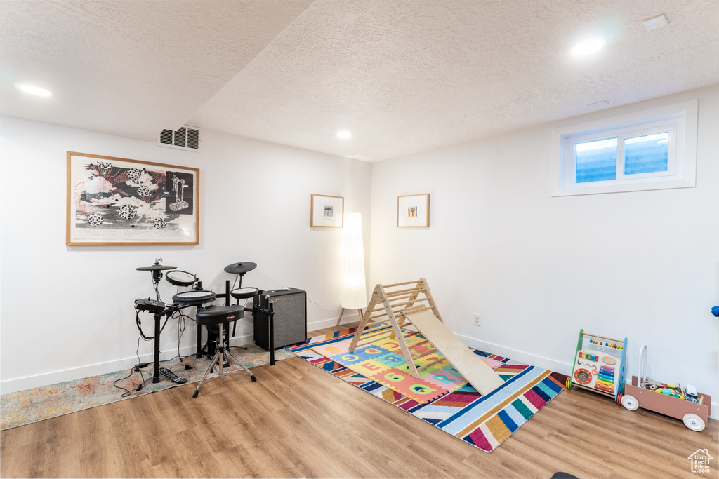 Recreation room featuring wood finished floors, a textured ceiling, recessed lighting, and baseboards