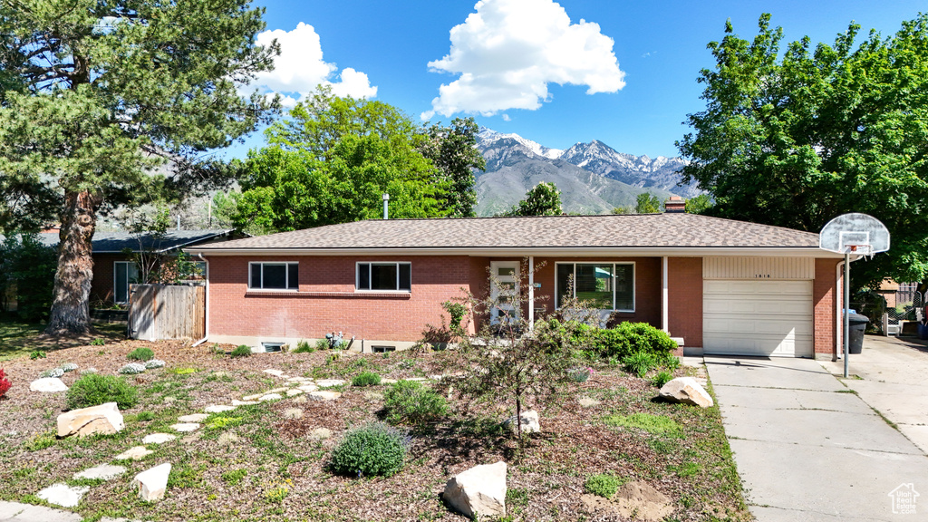 Ranch-style home featuring brick siding, a garage, a mountain view, and driveway