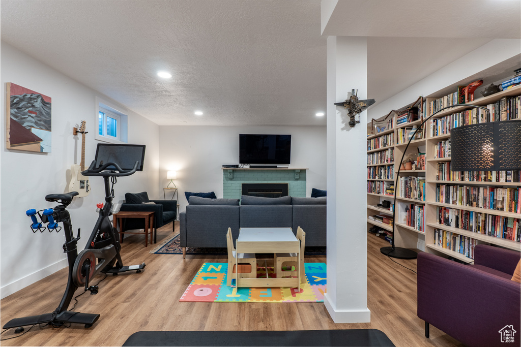 Workout area featuring a textured ceiling, a fireplace, wood finished floors, recessed lighting, and baseboards