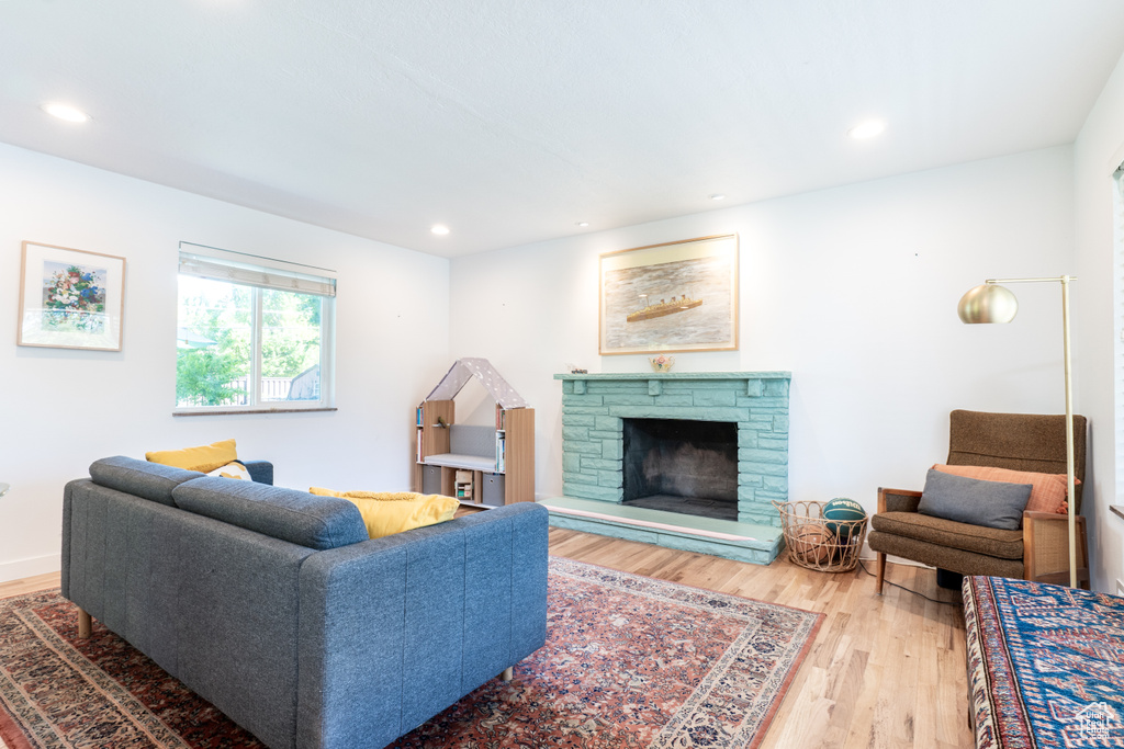 Living room with wood finished floors, a fireplace, and recessed lighting