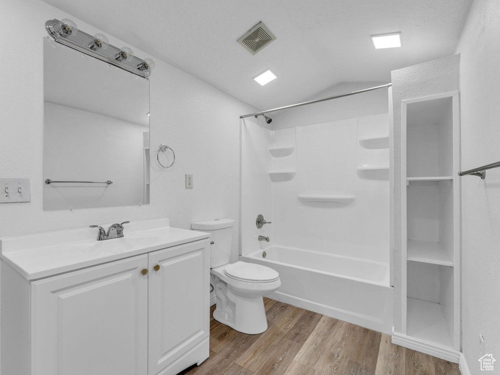 Bathroom featuring wood finished floors, toilet, vanity, and bathtub / shower combination