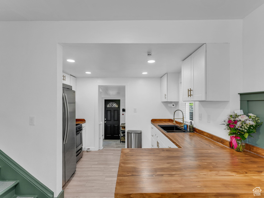Kitchen with a sink, range with gas stovetop, light wood-style flooring, white cabinetry, and recessed lighting