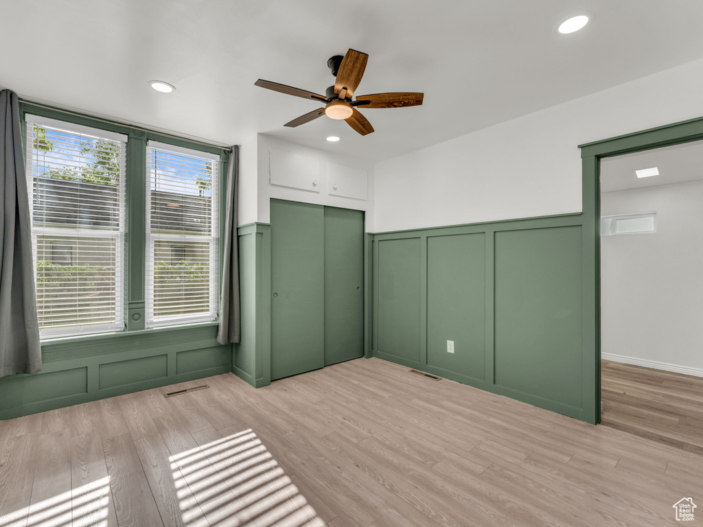Unfurnished bedroom with a decorative wall, light wood-style flooring, a wainscoted wall, recessed lighting, and a closet