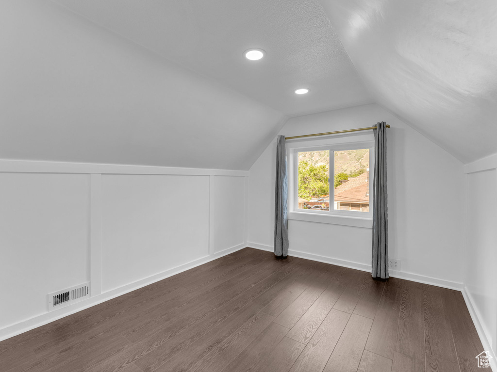 Bonus room with dark wood finished floors, lofted ceiling, baseboards, and recessed lighting