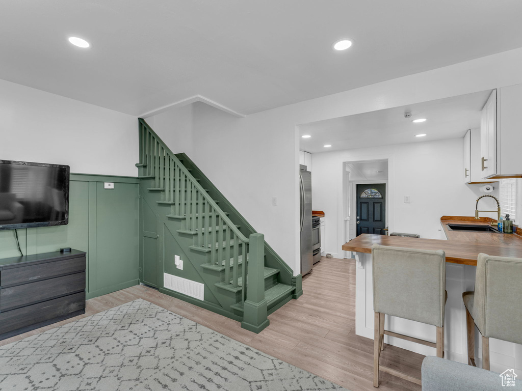Stairs with wood finished floors, recessed lighting, and wainscoting