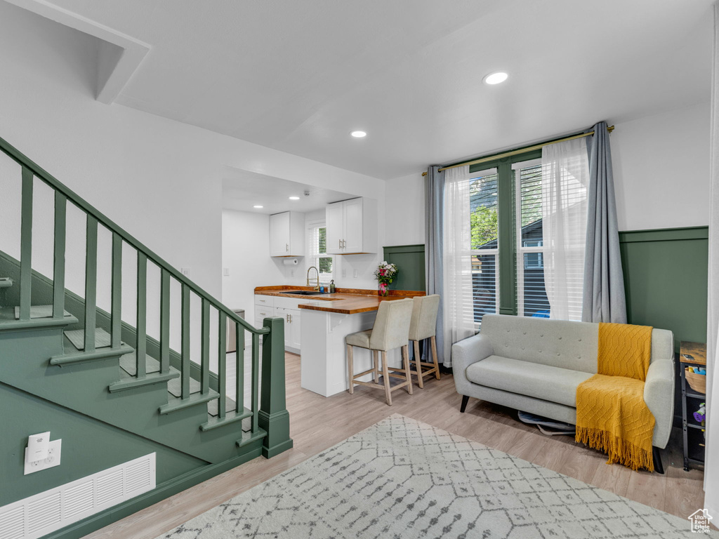 Living room featuring light wood-style flooring, recessed lighting, and stairs