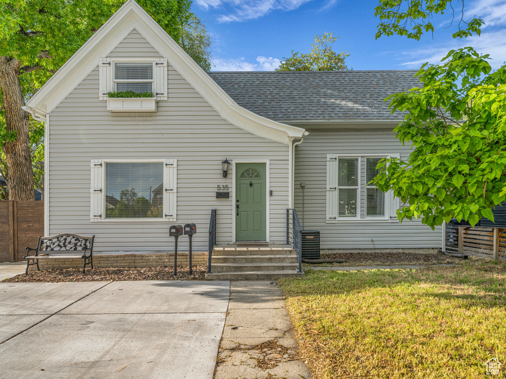 View of front of house with roof with shingles and a front lawn